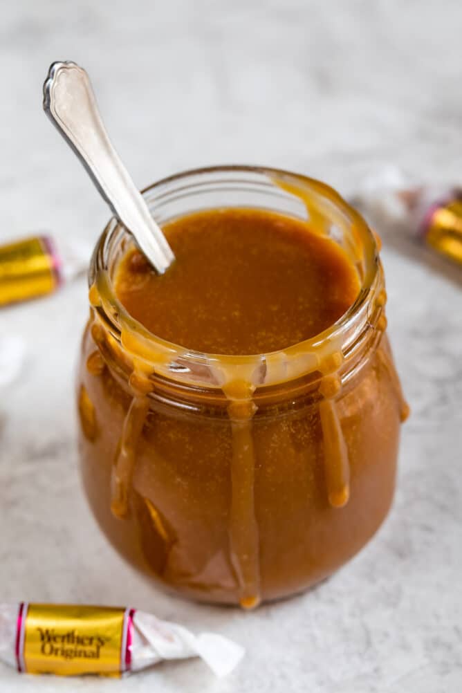 Three-ingredient caramel sauce in a jar with spoon inside