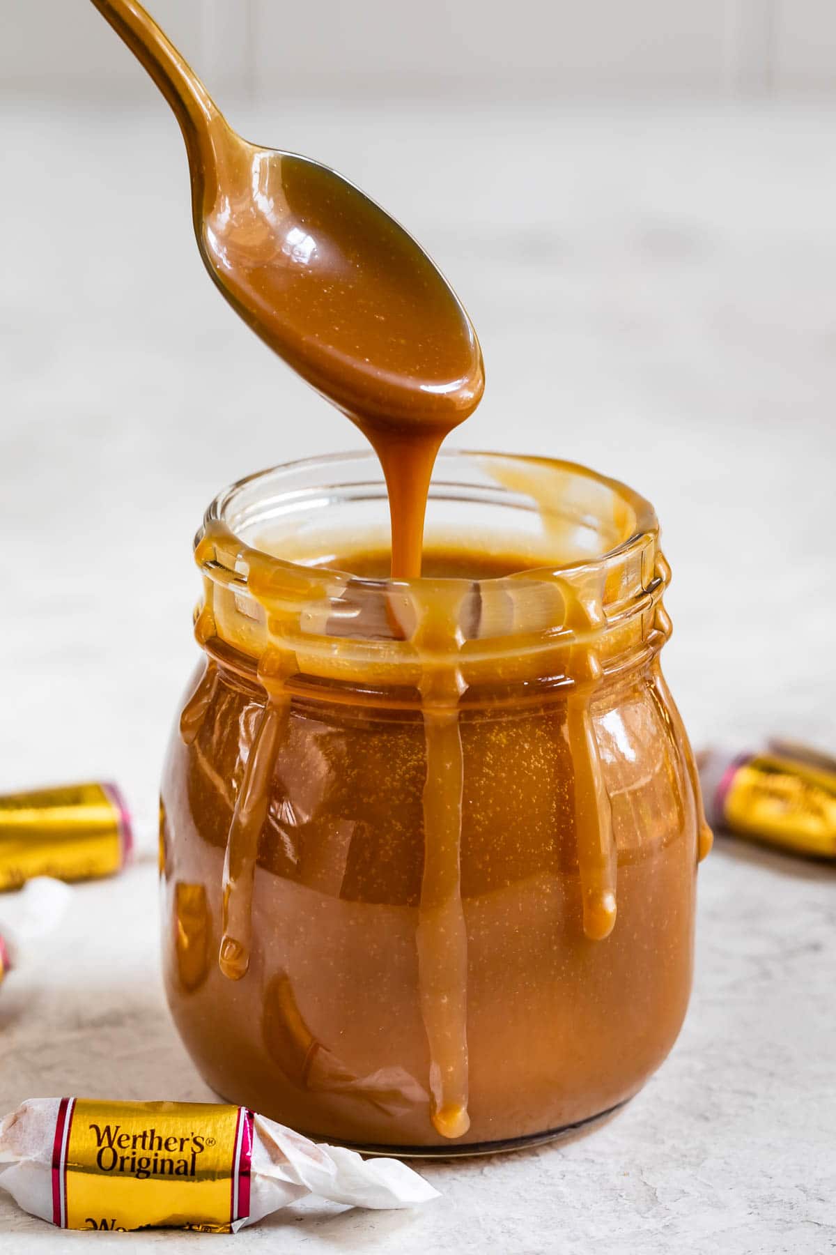 Spoonful of three-ingredient caramel sauce being poured back into the small jar