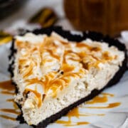 Close up shot of a slice of caramel cheesecake pie on a white scalloped plate