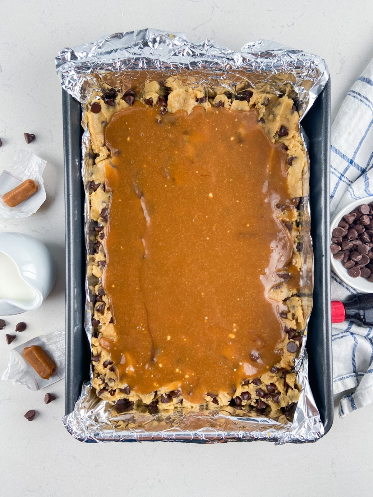 cookie dough in foil lined pan with caramel on top.