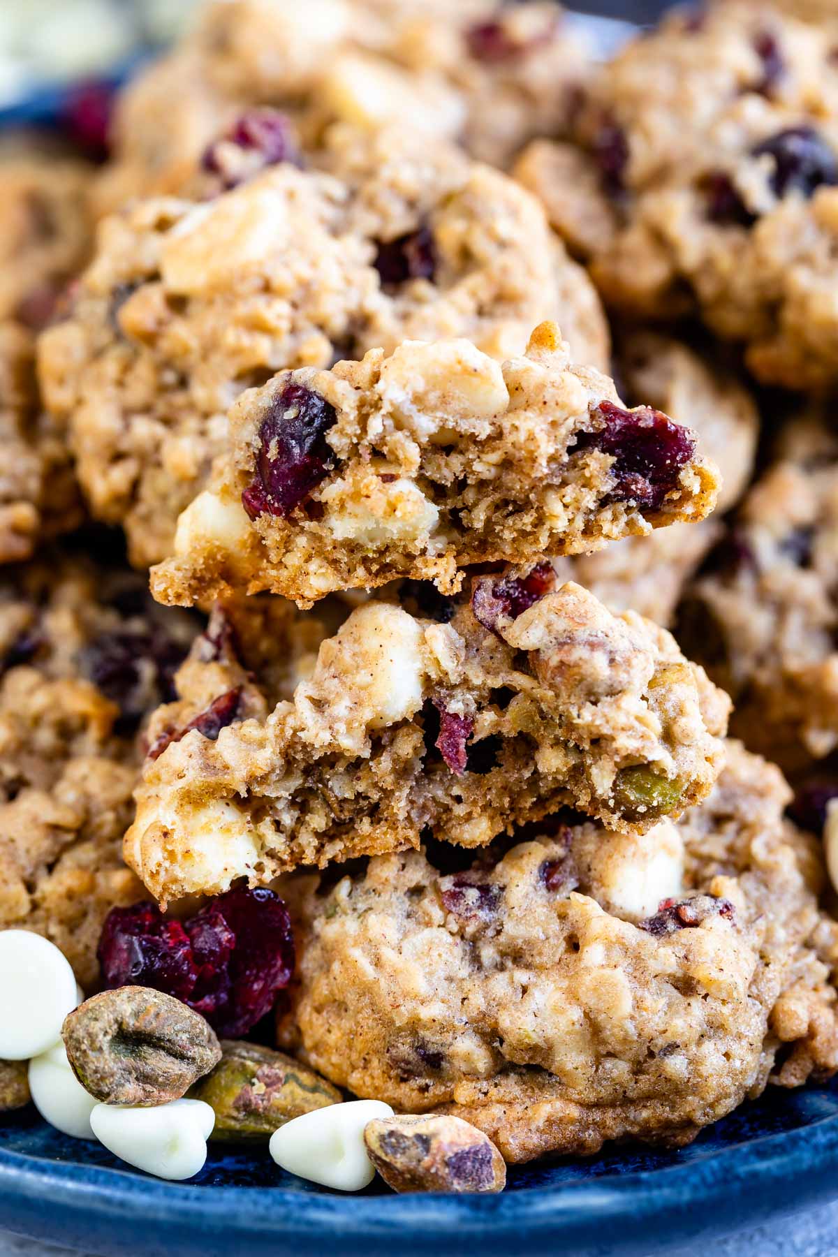 Close up shot of oatmeal cranberry cookies on a blue plate with one split in half to show inside of cookie