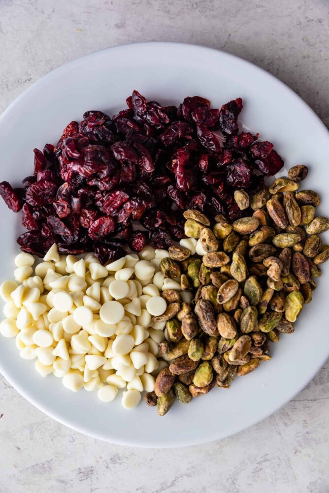 Overhead view of cranberries, white chocolate chips and pistachios on a plate