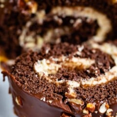 Close up shot of chocolate caramel turtle cake roll with one slice falling off