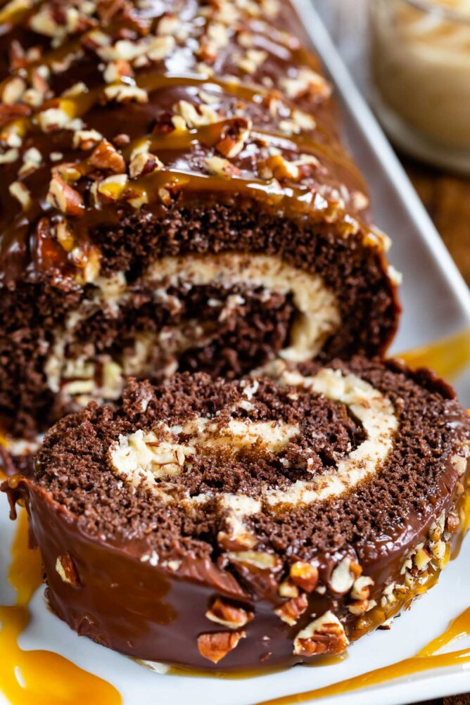 Chocolate caramel turtle cake roll with one slice falling off