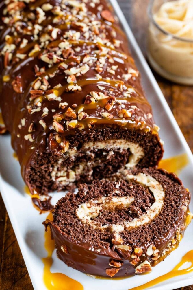 Chocolate caramel turtle cake roll with one slice falling off