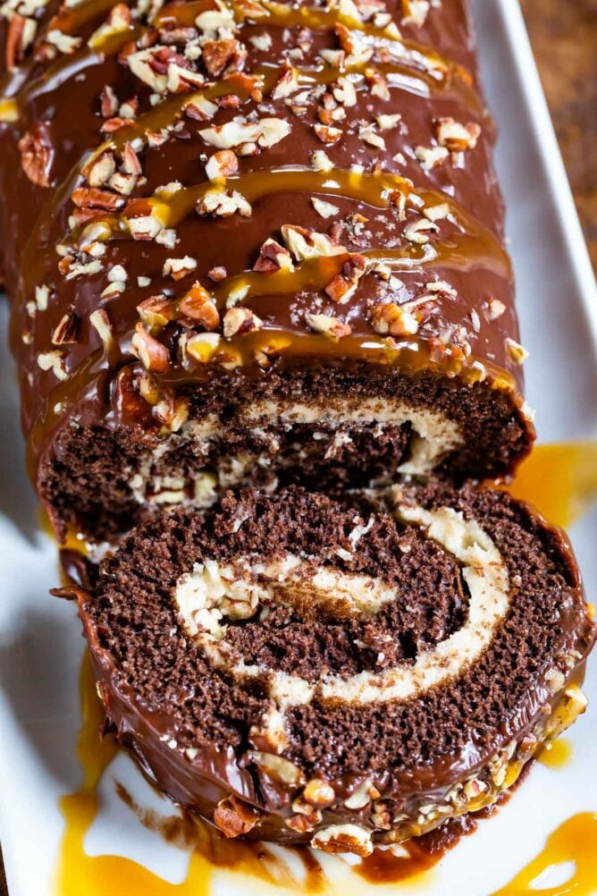 Overhead shot of caramel chocolate turtle cake roll with one slice cut off