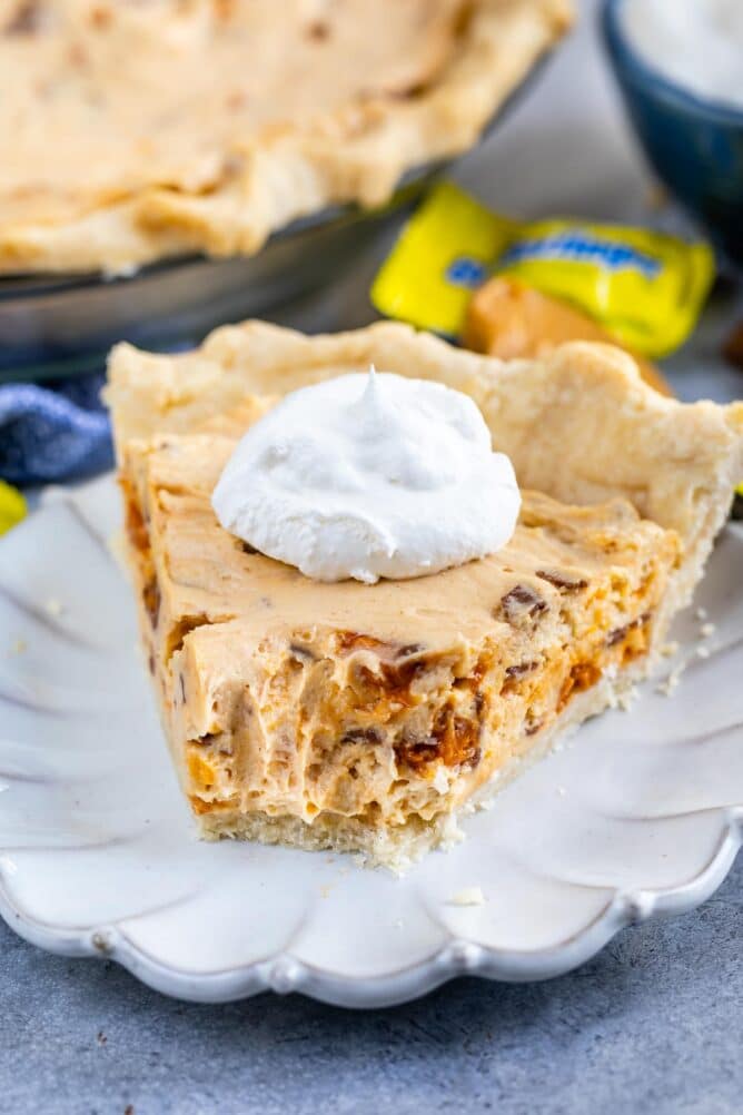 One slice of easy butterfinger pie with a dollop of whipped cream and one bite missing