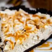 Close up shot of a slice of caramel cheesecake pie on a white scalloped plate with recipe title on top of image