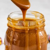 Spoonful of three-ingredient caramel sauce being poured back into the small jar with recipe title on top of image