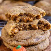 Caramel stuffed pumpkin cookies with top one cut in half to show inside caramel filling