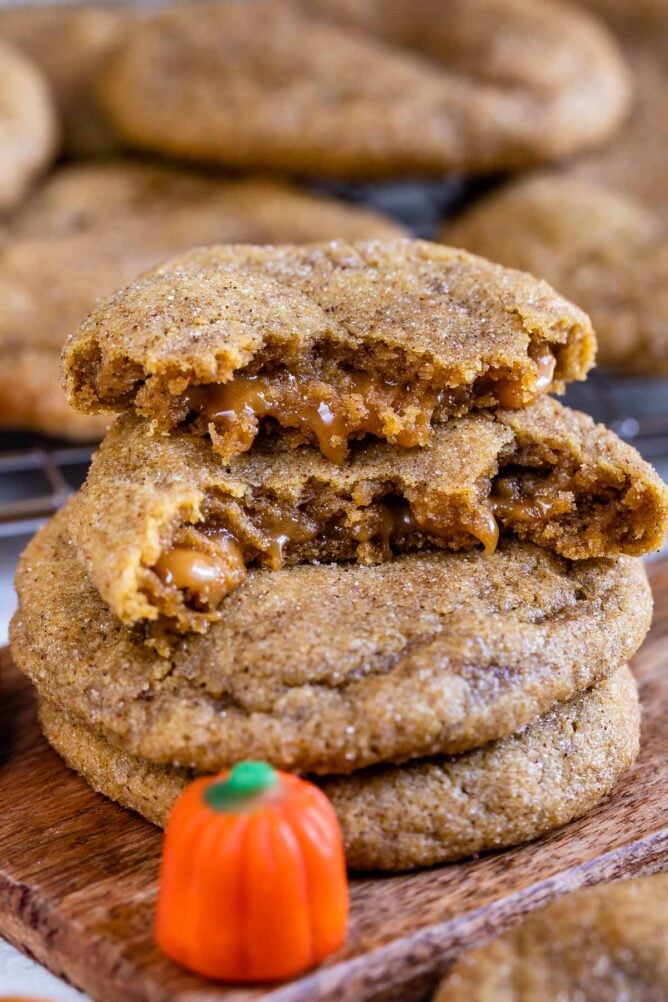 Caramel stuffed pumpkin cookies with top one cut in half to show inside caramel filling