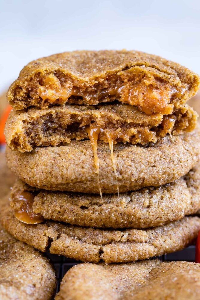 Caramel stuffed pumpkin cookies with top one cut in half to show inside caramel filling