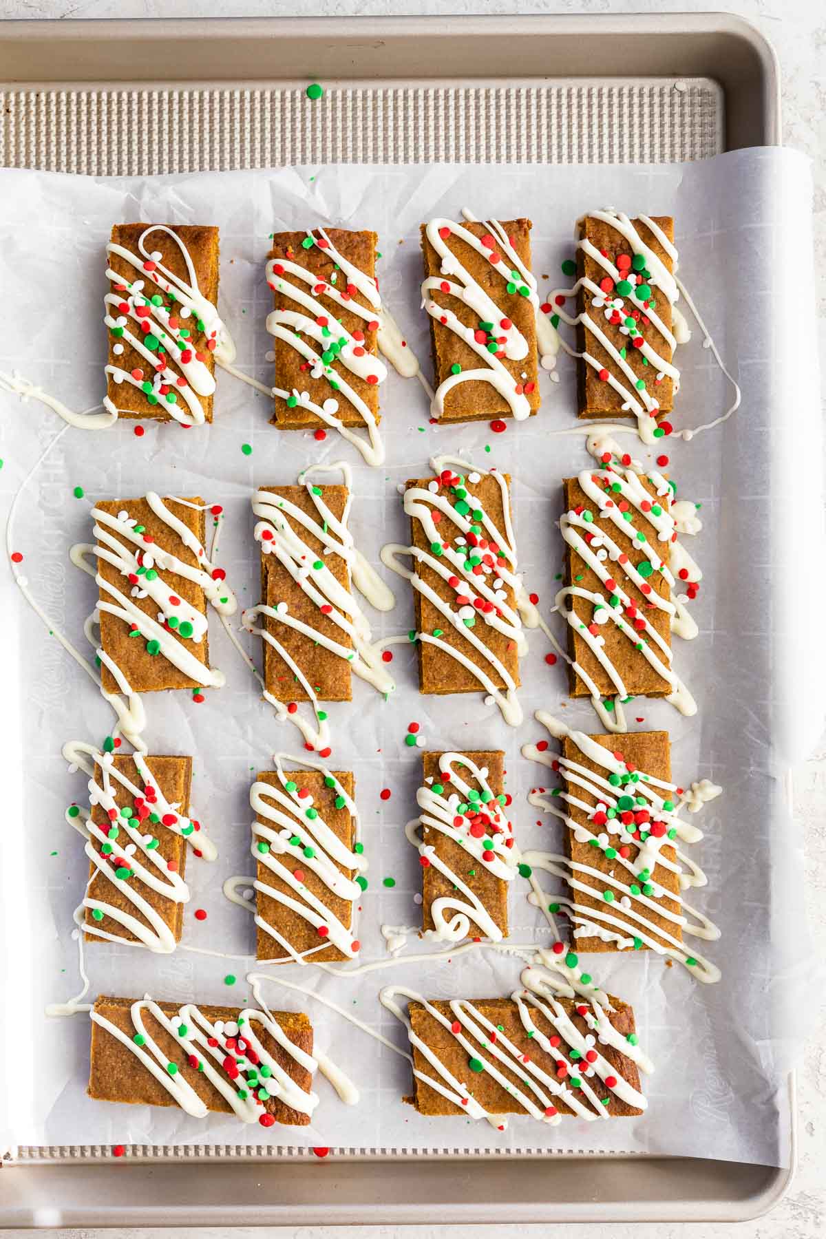 Overhead shot of decorated gingerbread cookie bars on parchment paper