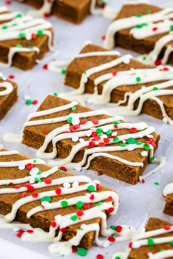 Close up shot of gingerbread cookie bars decorated with white icing and red and green sprinkles