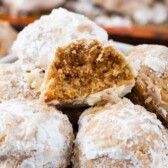 Close up shot of bowl of gingerbread snowball cookies with one split in half to show inside of cookie with recipe title on top of image