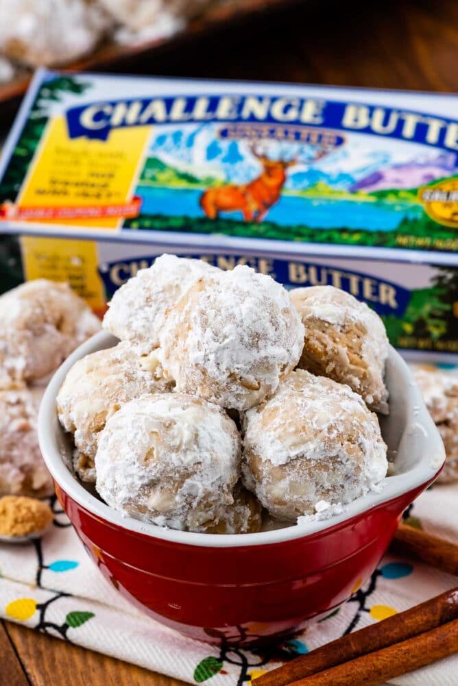 Red bowl of gingerbread snowballs with challenge butter in the background