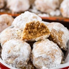 Close up shot of bowl of gingerbread snowball cookies with one split in half to show inside of cookie