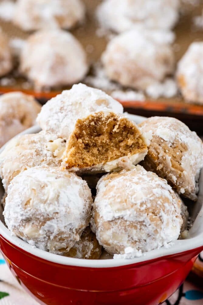 Close up shot of bowl of gingerbread snowball cookies with one split in half to show inside of cookie