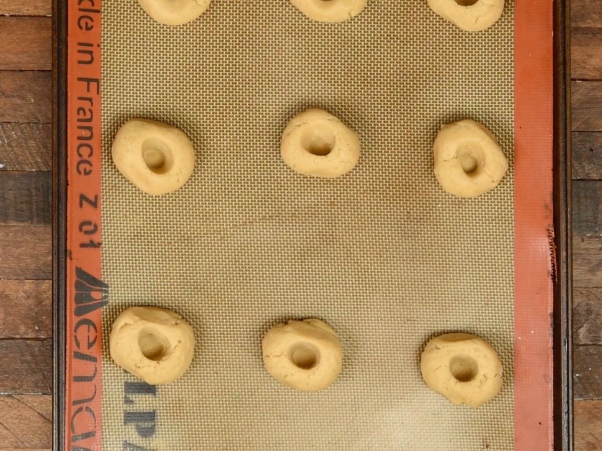 cookie dough with thumbprints on cookie sheet