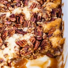 Pecan pie cobbler in a white baking dish with corner piece missing