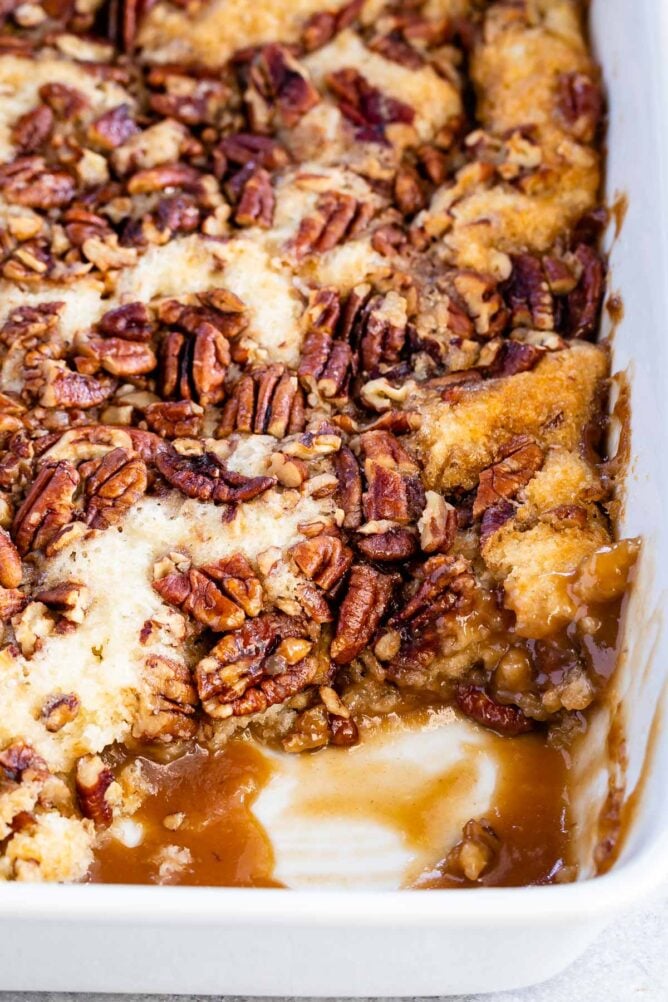Pecan pie cobbler in a white baking dish with corner piece missing