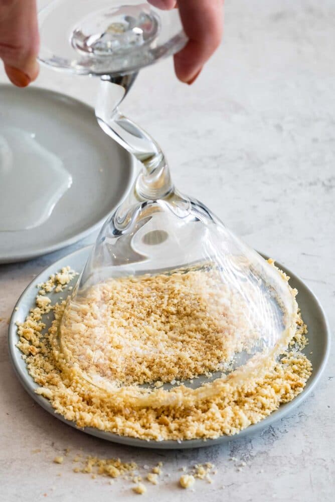 martini glass dipping in cookie crumbs on gray plate