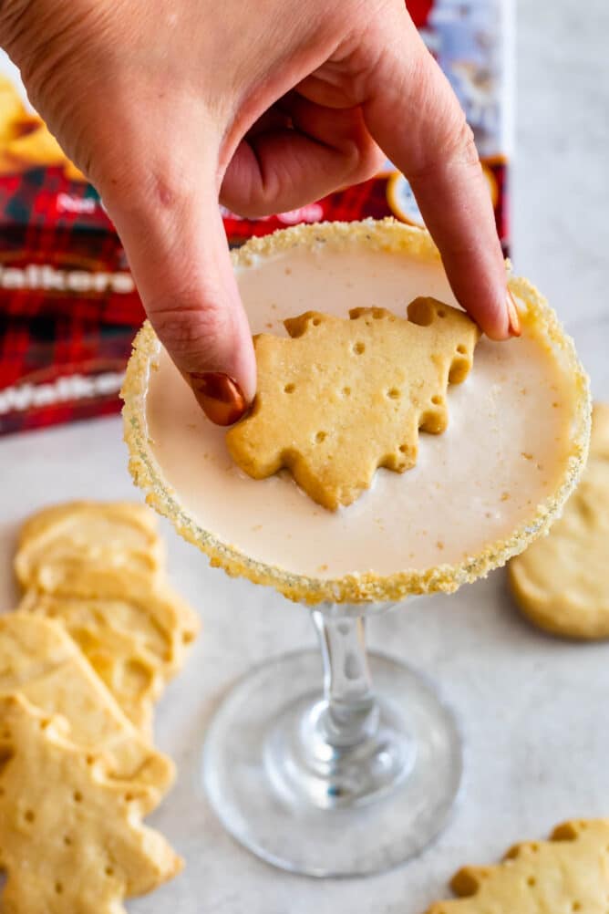 hand placing christmas tree shaped shortbread cookie in martini