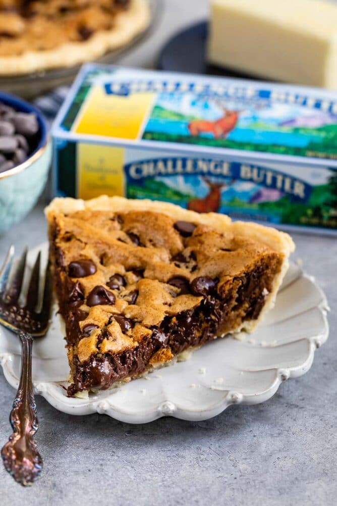 slice of chocolate chip cookie pie on white plate with butter box behind