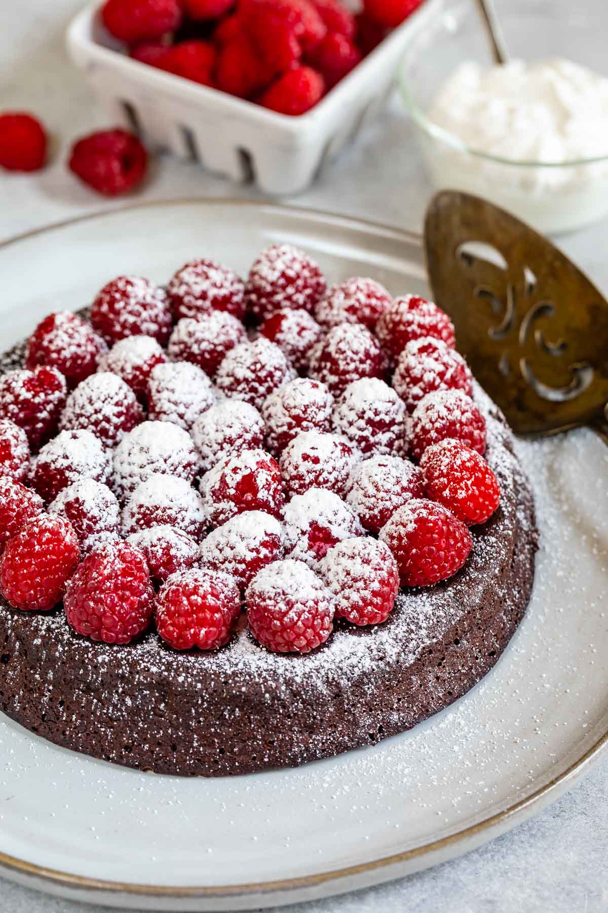 Flourless chocolate cake topped with raspberries and powdered sugar