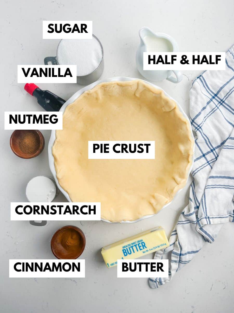 A labeled top-down view of ingredients for a sugar cream pie recipe: sugar, half & half, vanilla, nutmeg, cornstarch, cinnamon, butter, and a pie crust in a dish, all arranged on a white surface with a striped towel.