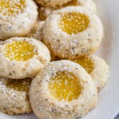 stack of thumbprint cookies filled with lemon curd on white plate