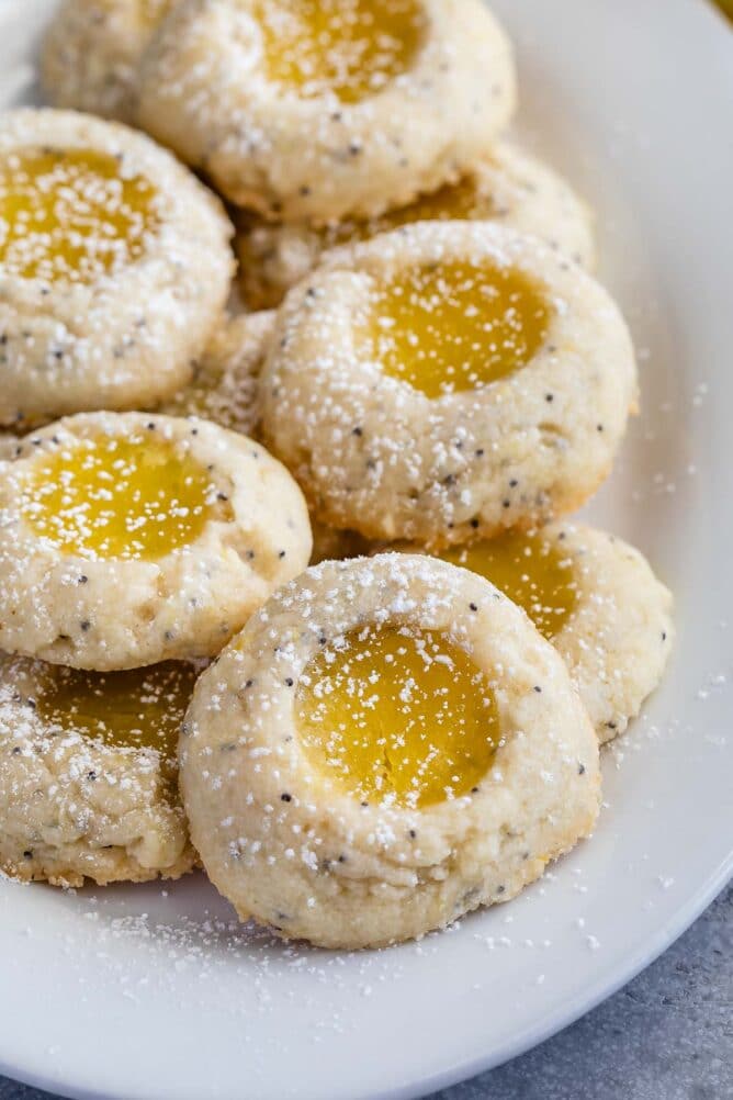 stack of thumbprint cookies filled with lemon curd on white plate