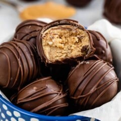 blue bowl with peanut butter balls inside and one cut in half