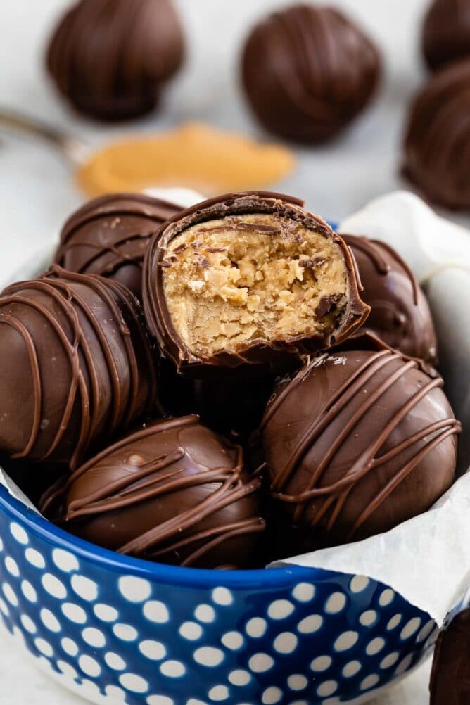 blue bowl with peanut butter balls inside and one cut in half