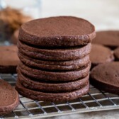 Stack of chocolate shortbread cookies on a metal cooling rack