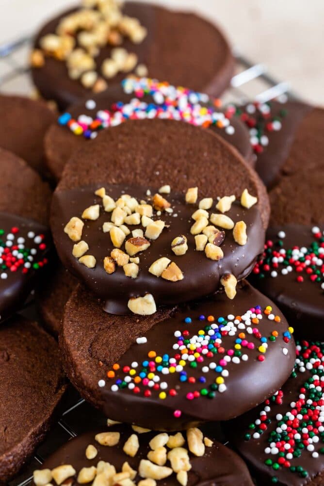 Chocolate shortbread cookies dipped in chocolate and topped with sprinkles and nuts