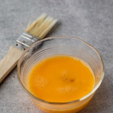 beaten egg in bowl with pastry brush