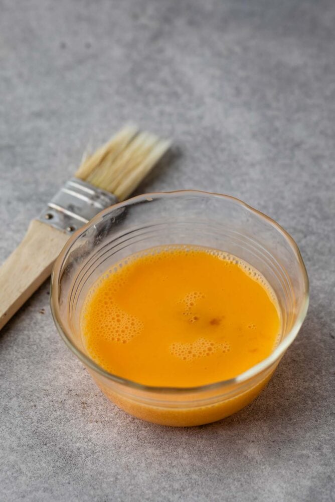 beaten egg in bowl with pastry brush