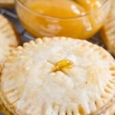 Lemon pie cookies on a metal cooling rack with a small bowl of lemon curd next to them and recipe title on top of image