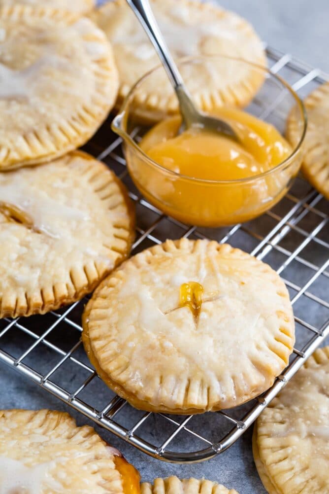Lemon pie cookies on a metal cooling rack with a small bowl of lemon curd next to them