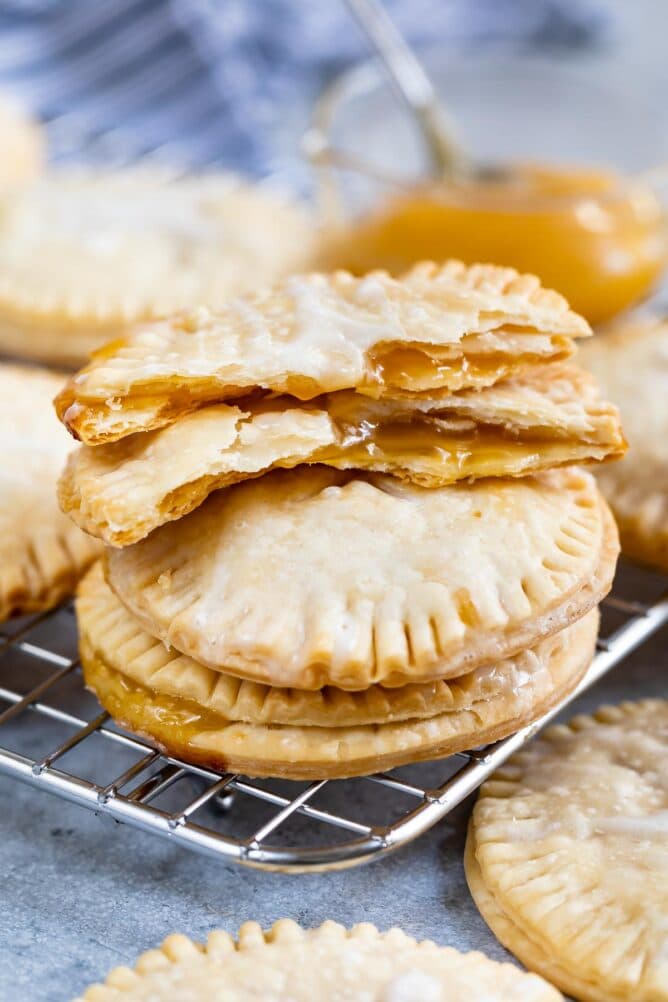 Stack of lemon pie cookies on a metal cooling rack with top one split in half to show filling