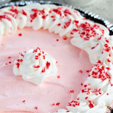 Peppermint pie topped with crushed candy canes and more in the background and recipe title on top of image