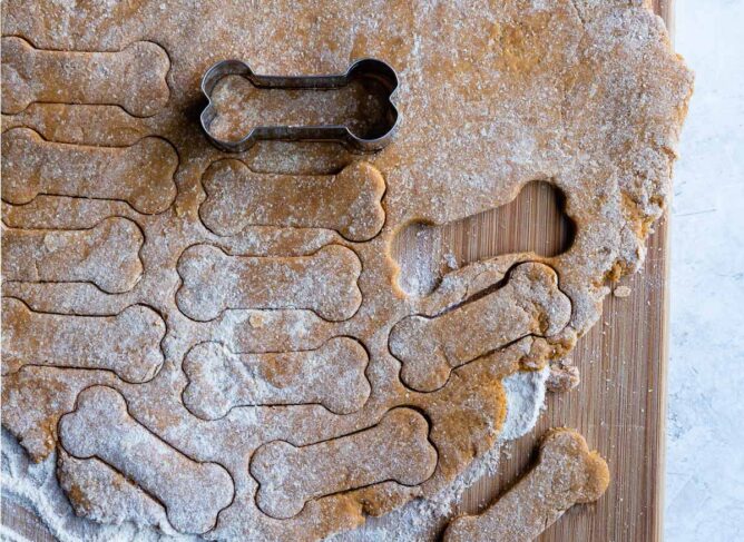 Overhead shot of dog cookie dough rolled out and cookie cutters being cut