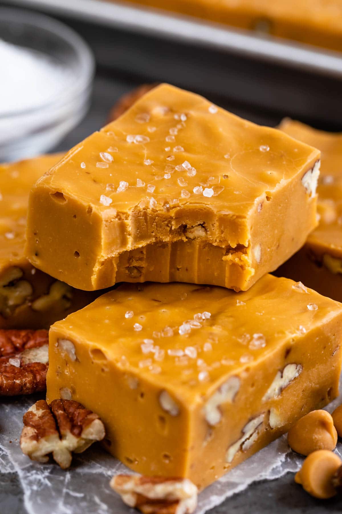 Two pieces of salted butterscotch fudge stacked on top of eachother with top piece missing a bite
