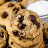 Three salted chocolate chip cookies stacked on top of eachother on a metal cooling rack