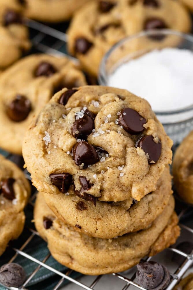 Three salted chocolate chip cookies stacked on top of eachother on a metal cooling rack