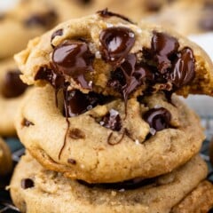 Three salted chocolate chip cookies stacked on top of eachother with top one cut in half to show melted chocolate chips on inside