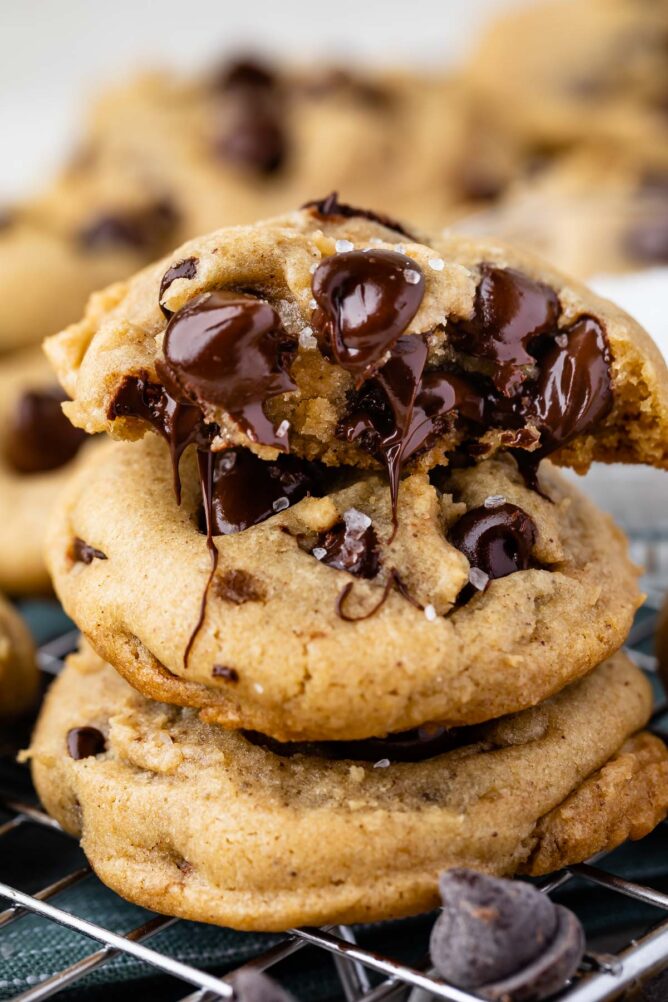 Three salted chocolate chip cookies stacked on top of eachother with top one cut in half to show melted chocolate chips on inside