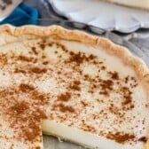 Sugar cream pie with one slice on a plate with fork behind pie and recipe title on top of image