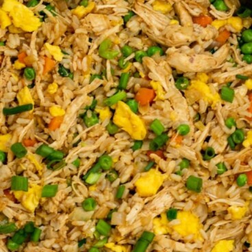 Overhead shot of chicken fried rice in frying pan with recipe title on top of image
